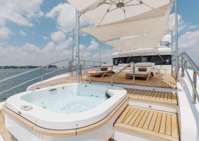 Luxury yacht deck with hot tub and chairs.