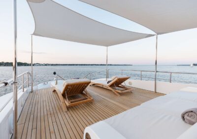 Lounge chairs on a yacht deck by water.