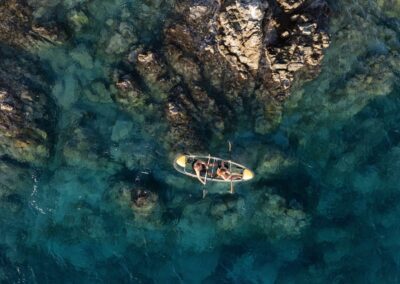 Two people kayaking over rocky seabed.